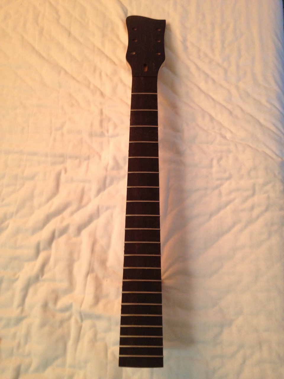 Close-up of a hand-carved guitar neck and fingerboard